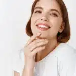 Smiling woman with short hair and a white shirt, showcasing a healthy smile, relevant to dental services and patient comfort at Dr. Chelsea Mason Dental.