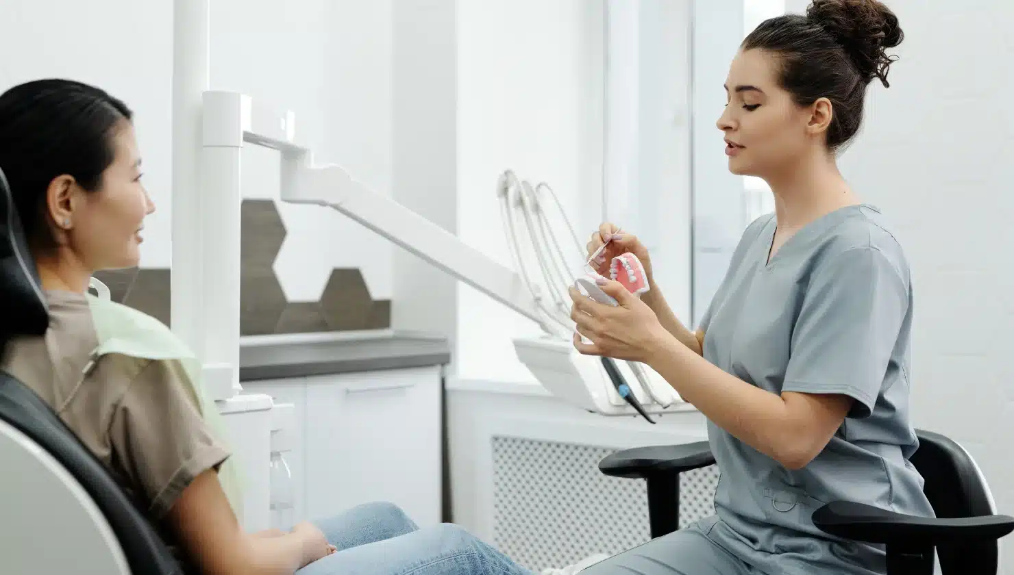 Dental professional demonstrating orthodontic treatment options with a patient in a dental office setting.