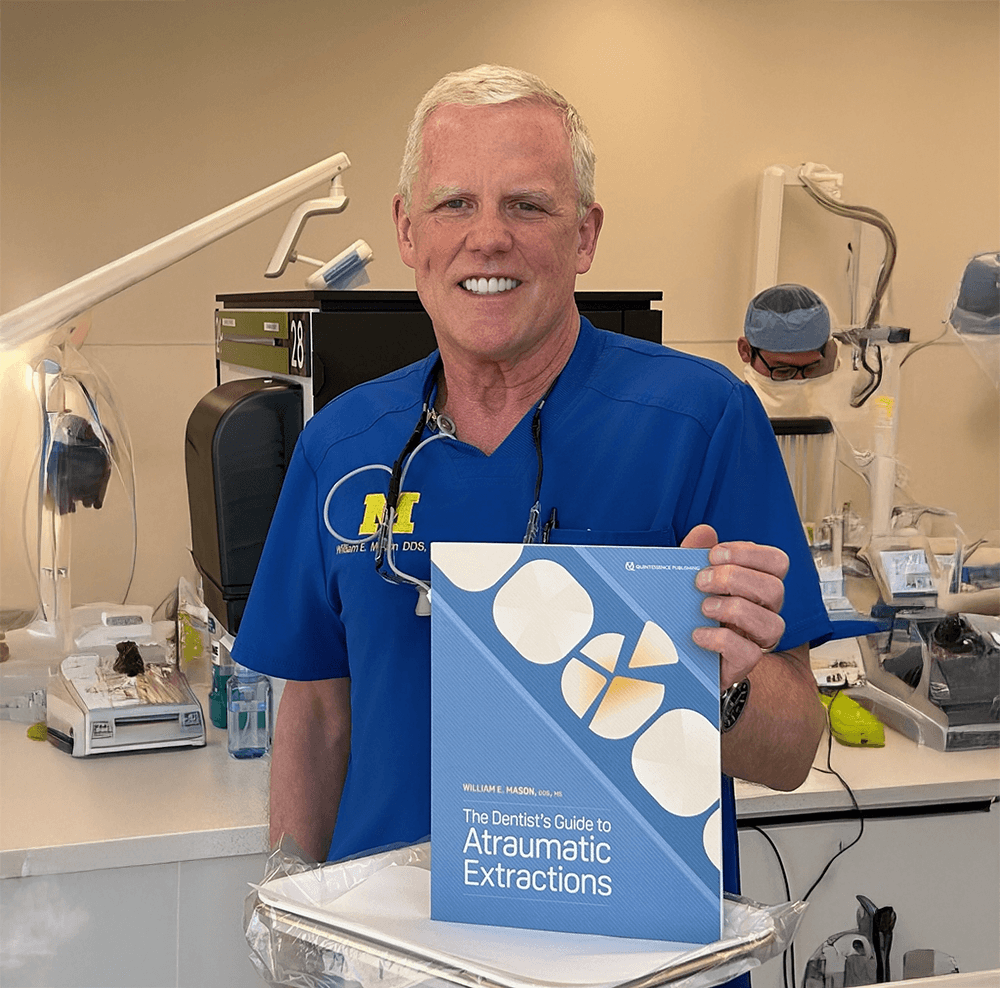 Dr. William Mason holding The Dentist's Guide to Atraumatic Extractions in the Bay City, MI office